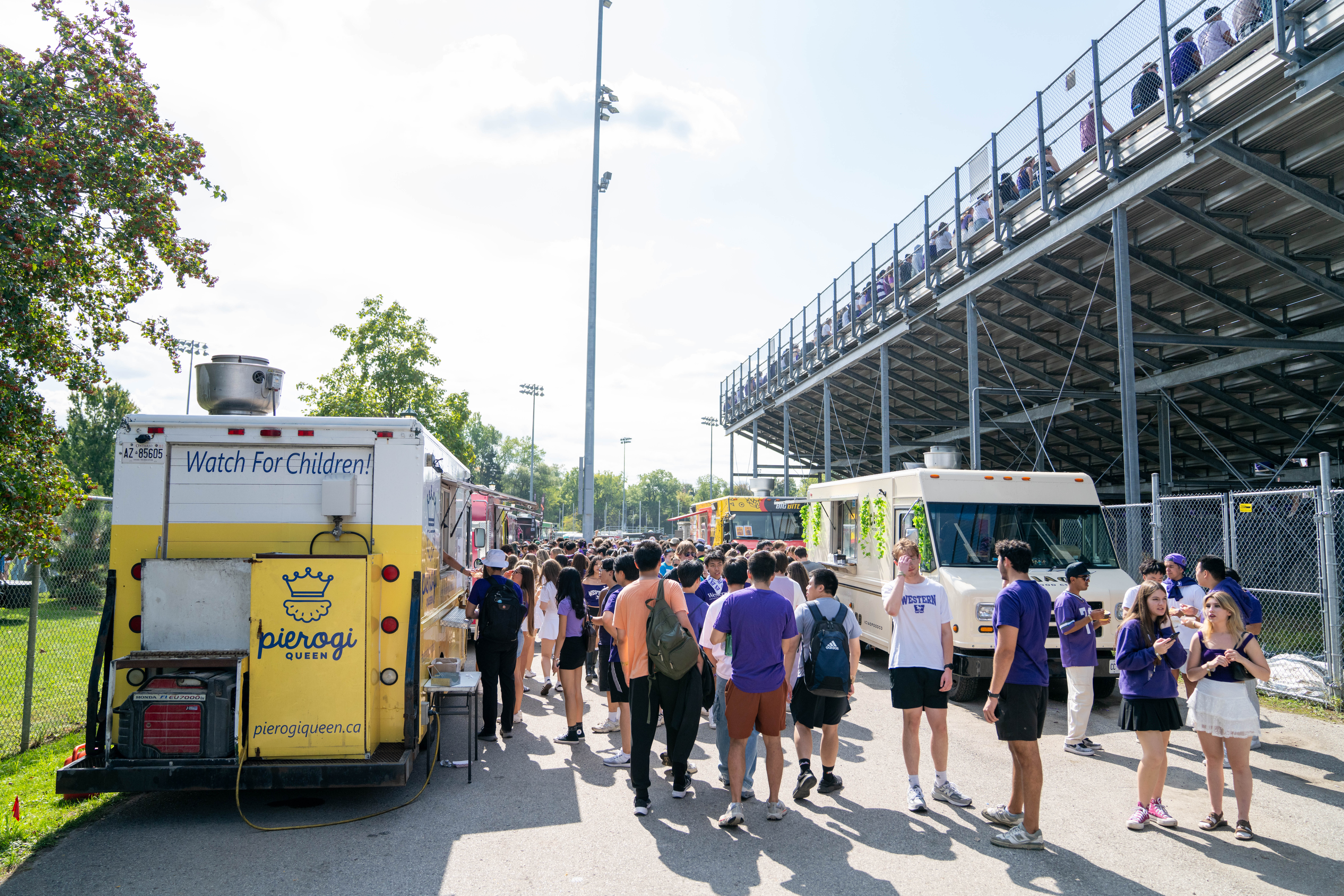 A large crowd of people lining up for various food trucks