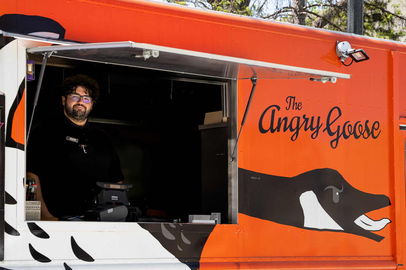 An employee posing at the register inside the Angry Goose food truck.